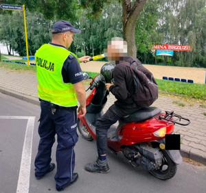 policjant stoi policjant stoi przy motocykliście i bada stan trzexwości kierowcy
