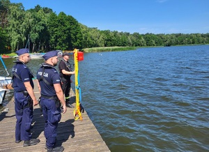 dwóch policjantów i strażak stoją na pomoście i oczekują na poszkodowanych