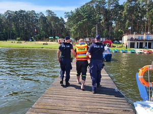 dwóch policjantów p[rowadzi poszkodowanego na ląd