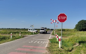 policjant i pracownik kolei stoją przy pojeździe,który zatrzymała się przed przejazdem kolejowym
