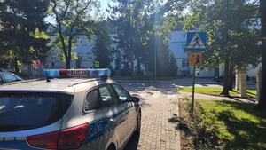 policjant stoi przy przejściu dla pieszych i sprawdza oznakowanie