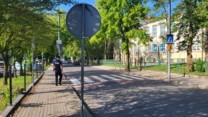policjant stoi przy przejściu dla pieszych i sprawdza oznakowanie