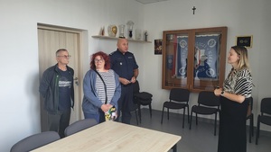 komendant oraz trzy osoby w sali na tle sztandaru