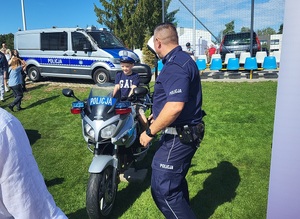 dziecki siedzące na policyjnym motocyklu, obok stoi policjant