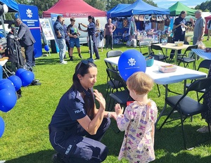 policjantka wręcza dziecko balon i podaje rekę