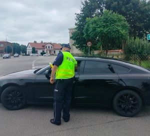 policjant stoi na drodze przy pojeździe i sprawdza stan trzexwości kierowcy