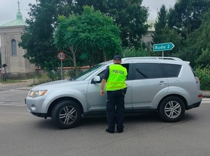 policjant stoi na drodze przy pojeździe i sprawdza stan trzexwości kierowcy