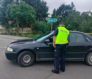 policjant stoi na drodze przy pojeździe i sprawdza stan trzexwości kierowcy