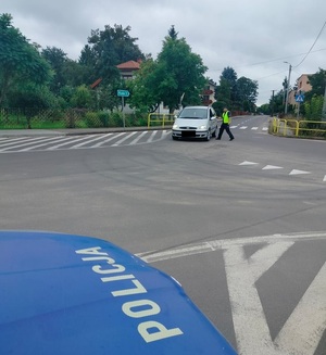 policjant stoi na drodze przy pojeździe i sprawdza stan trzexwości kierowcy