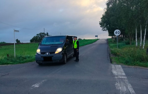 policjant stoi przy pojeździe i bada trzexwośc kierowcy