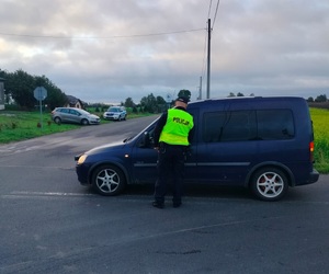 policjant stoi przy pojeździe i bada stan trzexwości kierowcy