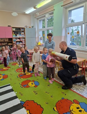 policjant prezentuje dzieciom tubę, w kolejce do obejrzenia ustawiły sie dzieci