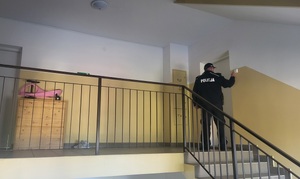 policjant w klatce schodowej puka do drzwi mieszkańców