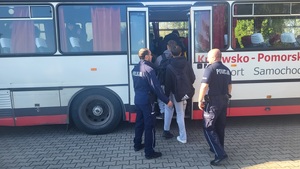 policjani pomagaja wsiadac do autokaru mieszkańcom